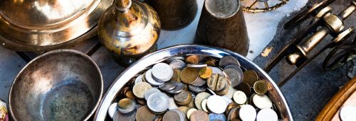 A collection of vintage brass items and coins arranged in a still life composition, showcasing historical artifacts.
