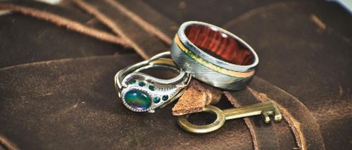 Close-up of exquisite rings on a leather journal with a vintage key, capturing elegance and craftsmanship.