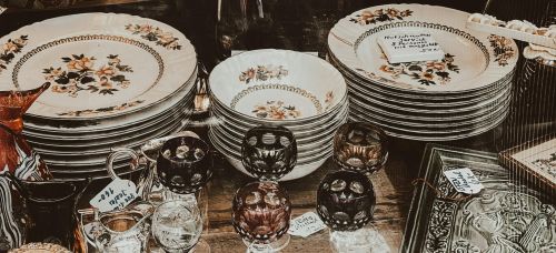 A vintage collection of porcelain dishes and glassware on display with an antique feel.